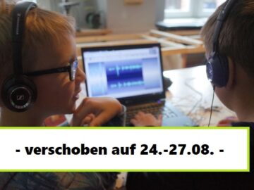 Zwei Jungen sitzen vor einem Laptop und schneiden eine Audiospur.